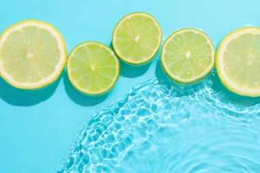 Açık mavi arka planda limon ve limon dilimleri, düz. Metin için boşluk