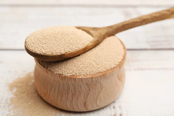 Kasede kuru maya ve kaşıkla beyaz ahşap masada, yakın plan.