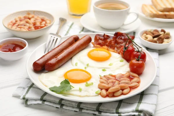Geleneksel İngiliz kahvaltısı. Lezzetli, güneşli, pastırmalı yumurta ve sosisler beyaz ahşap masada servis ediliyor, yakın plan.