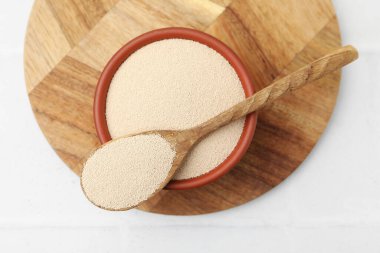 Kasede kuru maya ve kaşıkla beyaz fayanslı masa, üst manzara.