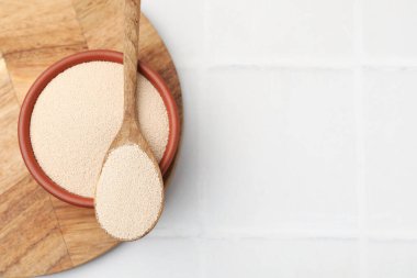 Kasede kuru maya ve kaşıkla beyaz fayanslı masa, üst manzara. Metin için boşluk