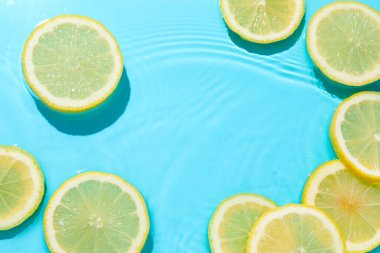 Açık mavi arka planda limon dilimleri, düz. Metin için boşluk