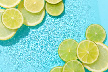 Açık mavi arka planda limon ve limon dilimleri, düz. Metin için boşluk