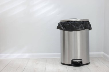 Kapalı mekanda yerde plastik torba olan metal çöp kutusu, metin için yer