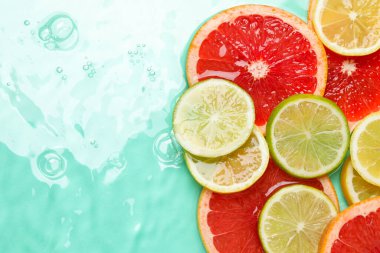 Turkuaz arka planda sudaki turunçgil meyveleri, düzlük. Metin için boşluk