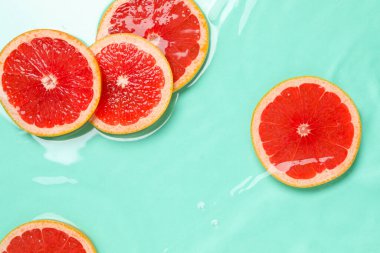 Turkuaz arka planda, suda greyfurt dilimleri, düzlük.