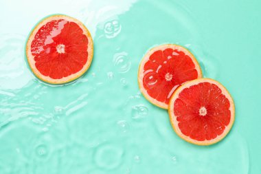 Turkuaz arka planda, suda greyfurt dilimleri, düzlük.