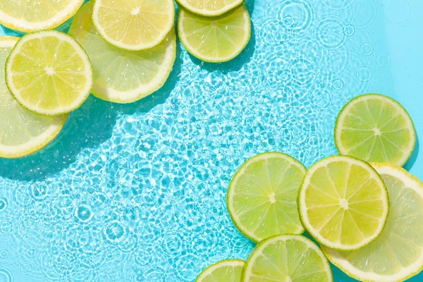 Açık mavi arka planda limon ve limon dilimleri, düz. Metin için boşluk