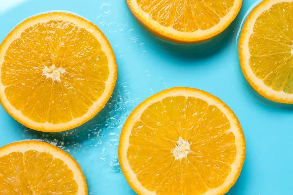 Açık mavi zemin üzerinde portakal dilimleri, düz uzanmış.