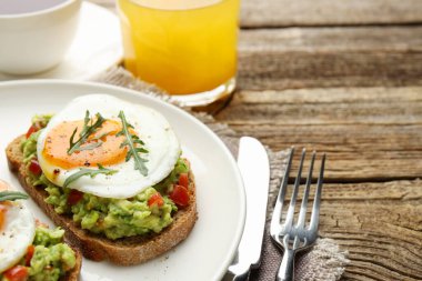 Avokado tostlu sağlıklı kahvaltı ahşap masada servis edilir, yakın plan. Metin için boşluk