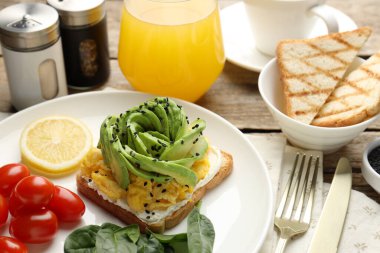 Avokado tostlu lezzetli kahvaltı ahşap masada servis edilir, yakın plan.