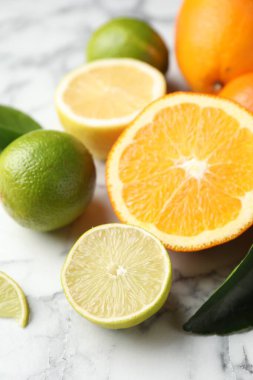 Beyaz mermer masada farklı olgun narenciye meyveleri, yakın plan.