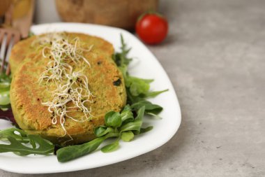 Mikroyeşillikli lezzetli vejetaryen köfteler ve gri masada salata, yakın plan. Metin için boşluk