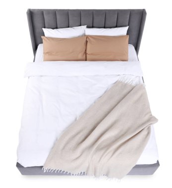 Büyük bir yatak, bej battaniyeli ve beyaz yastıklı.