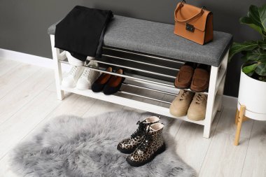 Gri duvarın yanında farklı ayakkabı, çanta ve çiçek depoları var.