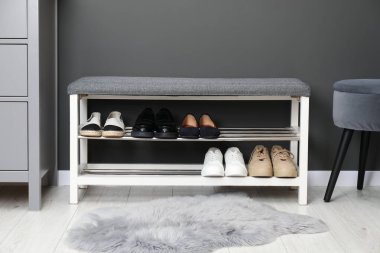 Gri duvarın yanında farklı ayakkabıları olan ayakkabı deposu.