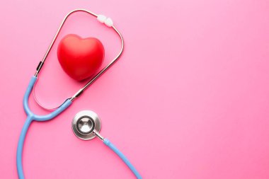 Pembe arka planda steteskop ve kırmızı kalp. Metin için boşluk