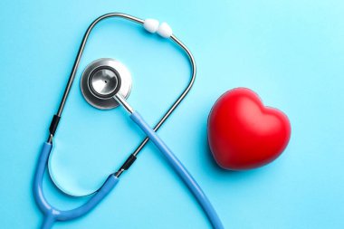 Açık mavi arka planda steteskop ve kalp modeli, üst görünüm