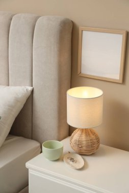 Şık lamba, fincan ve yüzükler evdeki komodinin yanında.