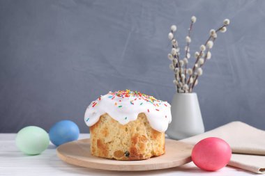 Lezzetli Paskalya pastası, boyanmış yumurtalar ve söğüt dalları beyaz ahşap masada.