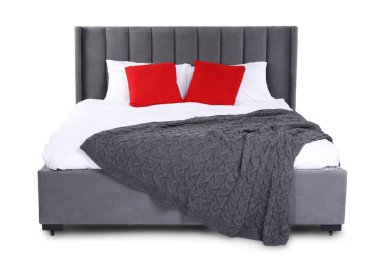 Gri battaniyeli büyük yatak ve beyaz yastıklı kırmızı yastıklar.