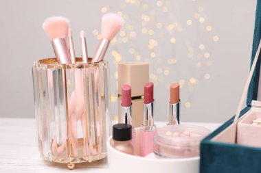 Makyaj ürünleri açık ahşap masa üzerinde gri arka planda, yakın plan. Bokeh etkisi