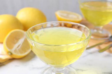 Tatlı kaselerinde leziz sarı jöle ve beyaz mermer masada taze limonlar, yakın plan.