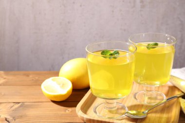 Tatlı kaselerinde lezzetli sarı jöle, nane ve ahşap masada taze limon, yakın plan. Metin için boşluk