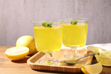 Tatlı kaselerinde leziz sarı jöle, nane ve taze limon ahşap masada, yakın plan.