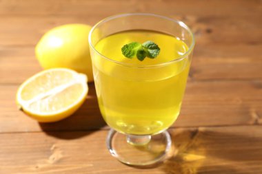 Tatlı kasesindeki lezzetli sarı jöle, nane ve taze limonlar ahşap masada, yakın plan.