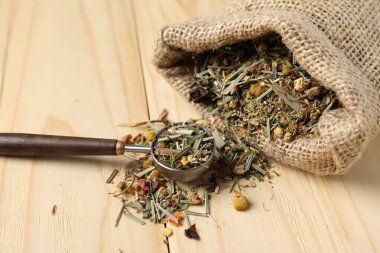 Çuvalda kurutulmuş bitki çayı ve tahta masada kaşık, yakın plan.