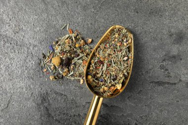 Kurumuş yeşil çay yaprakları ve gri masada metal spatula.