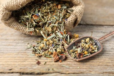 Çuvalda kurutulmuş bitki çayı ve ahşap masada metal spatula, yakın plan.