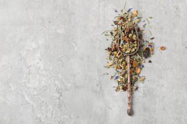 Açık gri masada kurutulmuş bitki çayı ve metal spatula, üst manzara. Metin için boşluk