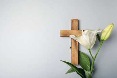 Paskalya. Ahşap haç ve gri arkaplanda zambak çiçekleri, metin için boşluk ile üst görünüm