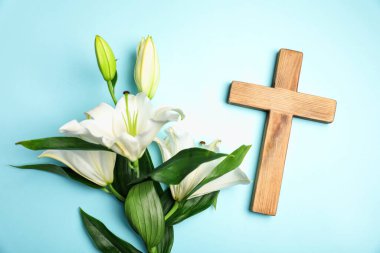 Paskalya. Tahta haç ve açık mavi arka planda güzel zambak çiçekleri, düz yatıyordu.