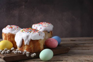 Lezzetli Paskalya pastaları, boyanmış yumurtalar ve tahta masanın üzerinde söğüt dalları, yakın plan. Metin için boşluk