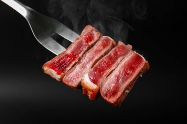 Et çatalı üzerine sığır eti parçaları siyah arkaplan karşı