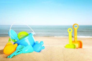 Deniz kenarındaki kumda parlak plastik plaj oyuncakları. Yaz zamanı.