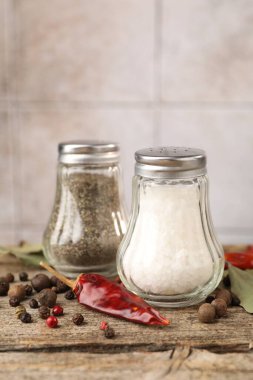 Ahşap masada baharatlı tuzluklar ve biberlikler bulanık arka planda, yakın plan