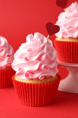 Sevgililer Günün kutlu olsun. Kırmızı arka planda kalp kapakları olan lezzetli kekler, yakın plan.