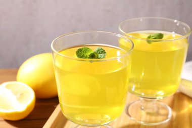 Tatlı kaselerinde leziz sarı jöle, nane ve taze limon ahşap masada, yakın plan.
