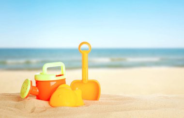 Deniz kenarındaki kumda parlak plastik plaj oyuncakları, pankart tasarımı. Yaz zamanı.
