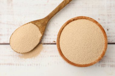 Kasede kuru maya ve kaşıkla beyaz ahşap masa, üst manzara.