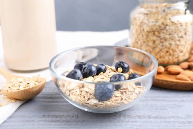 Yabanmersinli yulaf gevreği, badem sütü ve gri ahşap masada fındık, yakın plan.