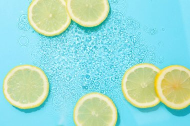 Açık mavi arka planda limon dilimleri, düz. Metin için boşluk