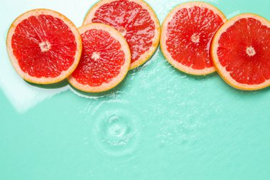 Turkuaz arka planda greyfurt dilimleri, düzlük. Metin için boşluk