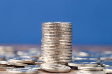 Masada mavi arkaplana karşı birikmiş paralar, yakın plan