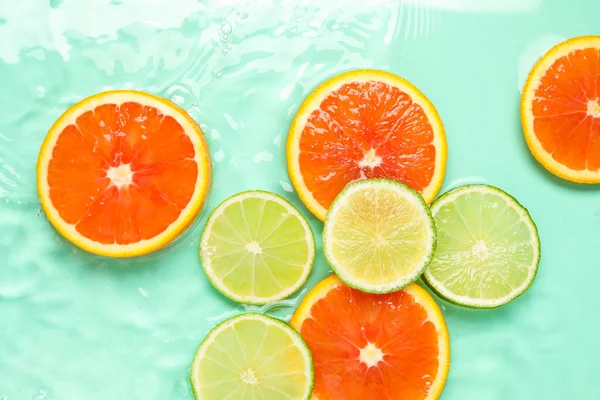 Turkuaz arka planda sudaki narenciye dilimleri, düzlük.