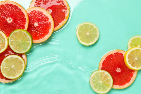 Turkuaz arka planda sudaki narenciye dilimleri, düzlük.